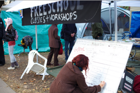 Rebecca, an occupy freeschool organizer, updates the whiteboard outside the Freeschool tent.