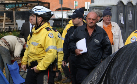 City workers, pushed by cops, put up eviction notices on tents, portapotties and other structures. (photo: Loretta Lime)