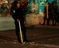 Nov. 25, 2009 - A police officer stamps out the embers of a fire lit in vigil for imprisoned President Zelaya.