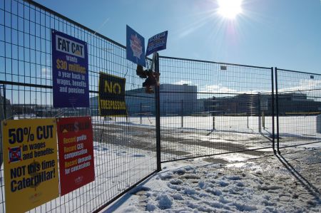 Protest signs and work boots hang off a fence at the front gate of the Electro-Motive Diesel plant in London, Ont. on Jan. 21. Photo: Mick Sweetman